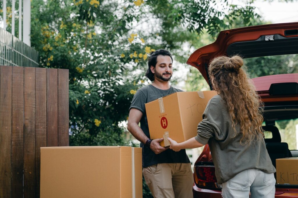 Couple passing carton box while unpacking