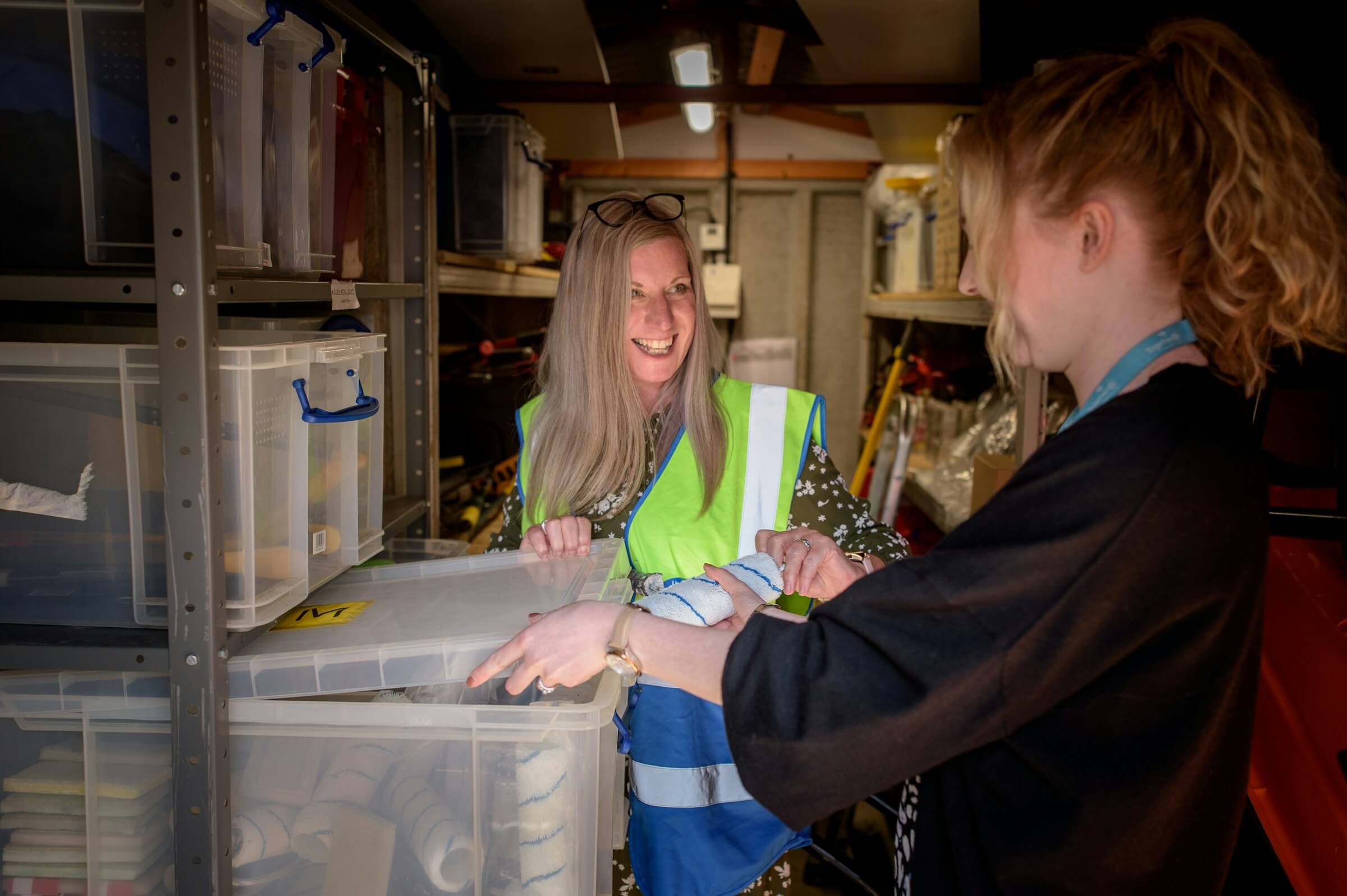 Two women smiling next to a box in a storage unit.